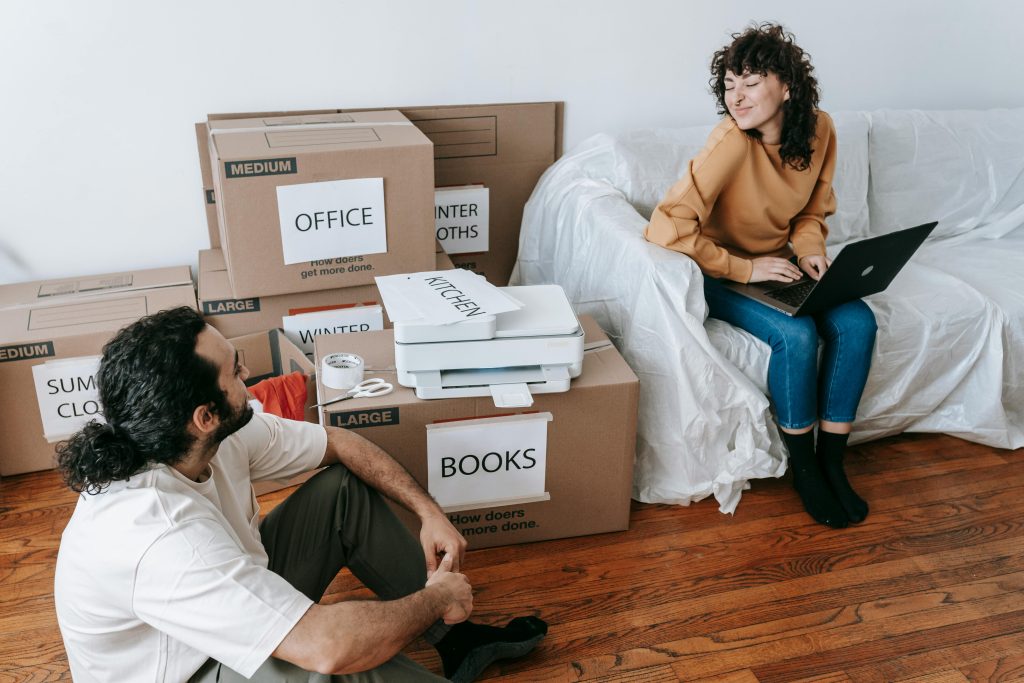 pexels photo 7218503 7218503 Young couple organizing boxes and relaxing with laptop during moving day indoors.