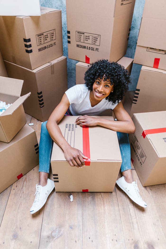 team-04 Happy woman sitting among boxes while packing for moving day. Perfect for relocation, moving, and lifestyle themes.
